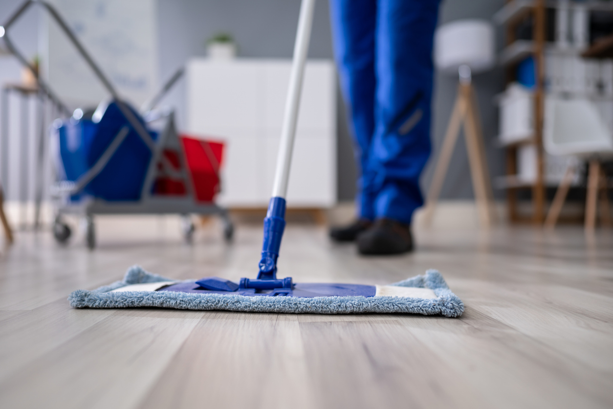 Happy Male Janitor Mopping Floor In Office